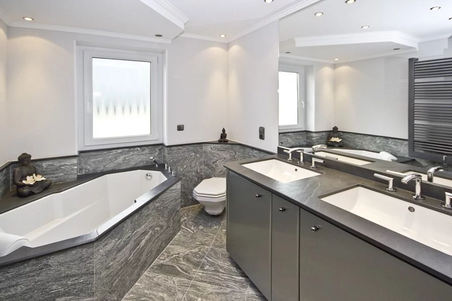 dunkeles Bad mit Baddewanne Toilette und einem großem Waschtisch