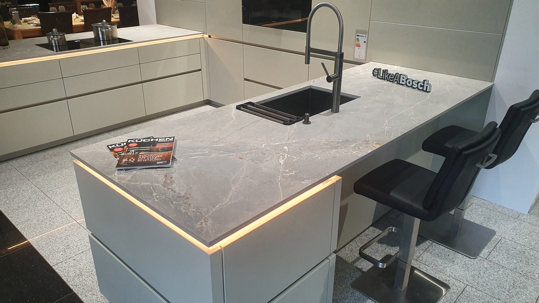 Weiße Küche mit Granitplatte, schwarzes Waschbecken sowie 2 schwarze Stühle