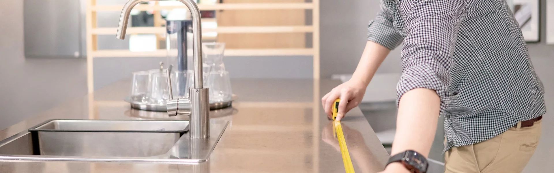 Bild ein Mann misst eine Arbeitsplatte in einer Küche aus.